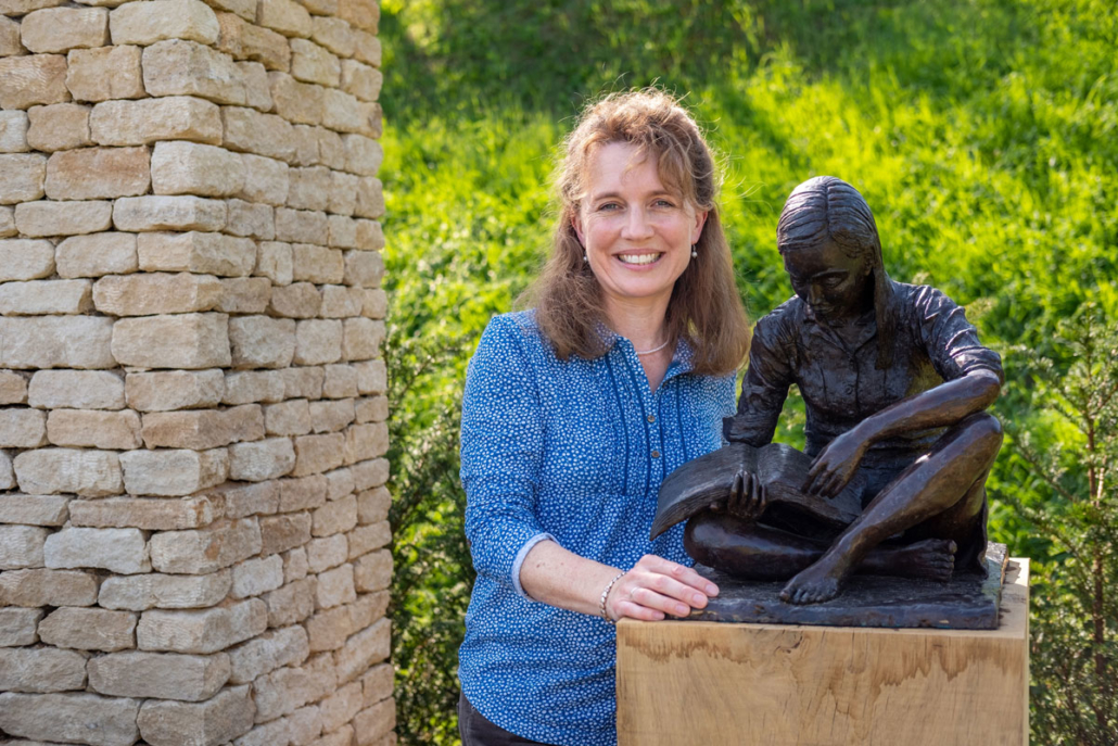 Anna Bromiley with her sculpture, Faith, installed in the garden.